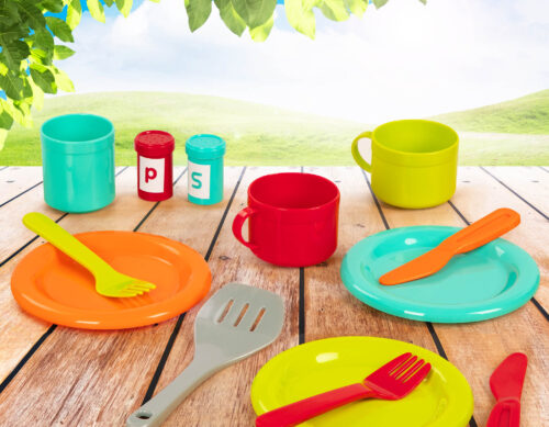 Colorful dishes, cutlery, cups, and more in an outdoor setting.