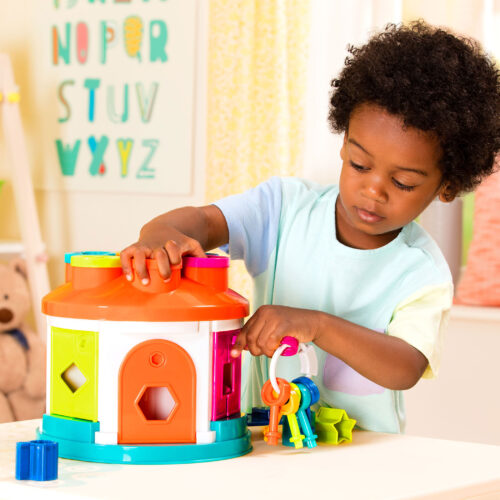 A child playing with a shape sorter house toy.