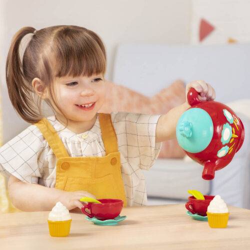 A kid playing with a singing tea pot toy.