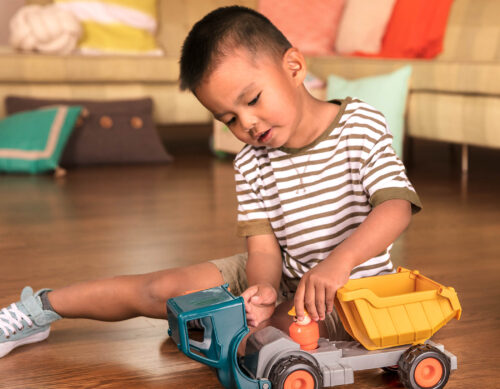 A kid playing with a toy dump truck.
