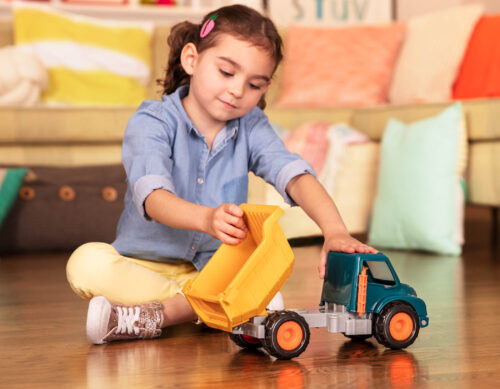 A kid playing with a toy dump truck.